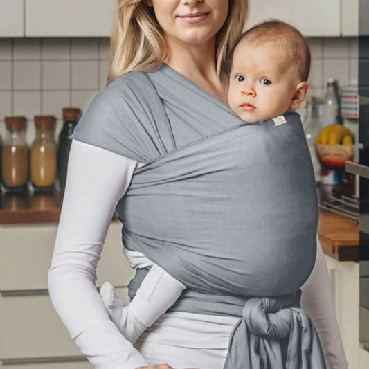 Portage ventral stable dans une echarpe de portage gris clair, maman en tenue blanche