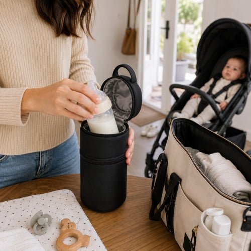 Étui antichoc pour biberon noir avec mise en place du biberon près d’un sac à langer