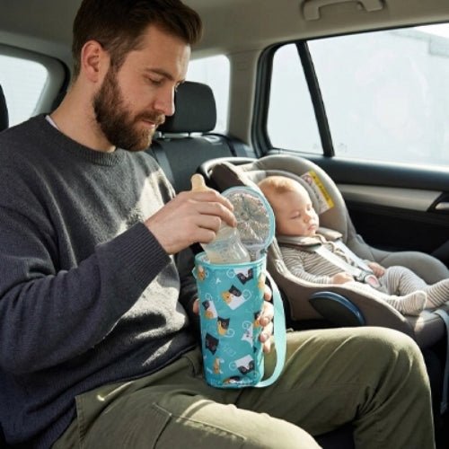 Étui imprimé pour biberon bleu motif chats ouvert avec biberon lors d’un déplacement en voiture