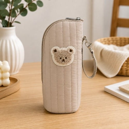 Étui matelassé pour biberon beige avec écusson ourson, vue de face et sangle amovible