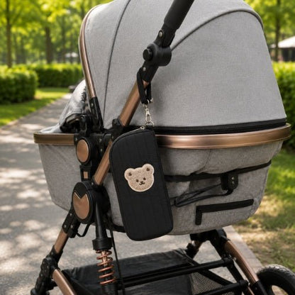 Étui matelassé pour biberon noir avec écusson ourson fixé à une poussette par sa sangle