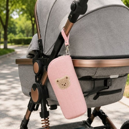 Étui matelassé pour biberon rose avec écusson ourson fixé à une poussette par sa sangle