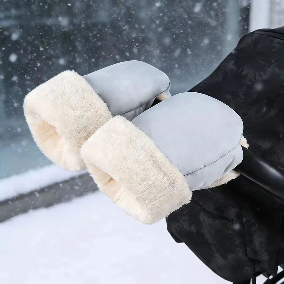 Paire de gants de poussette gris clair à ouvertures douces et duveteuses, présentée dans un décor hivernal