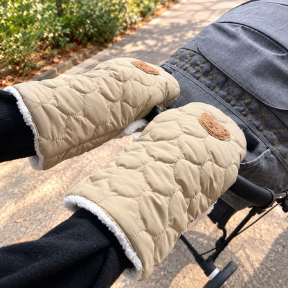 Paire de gants de poussette kaki clair matelassés à motif ourson, portés au guidon d'une poussette grise