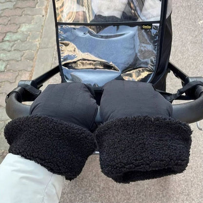 Gants de poussette noirs texturés avec larges revers bouclette, vus de face sur le guidon d'une poussette