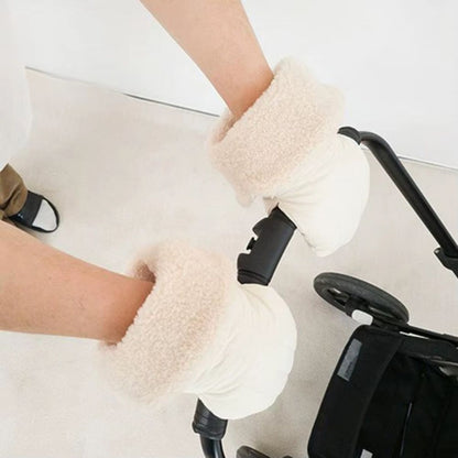 Gants de poussette texturés beige avec larges revers effet bouclette, portés sur le guidon noir d'une poussette