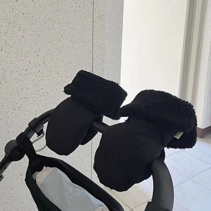 Vue latérale des gants de poussette texturés noirs avec revers pelucheux, placés sur un guidon courbé