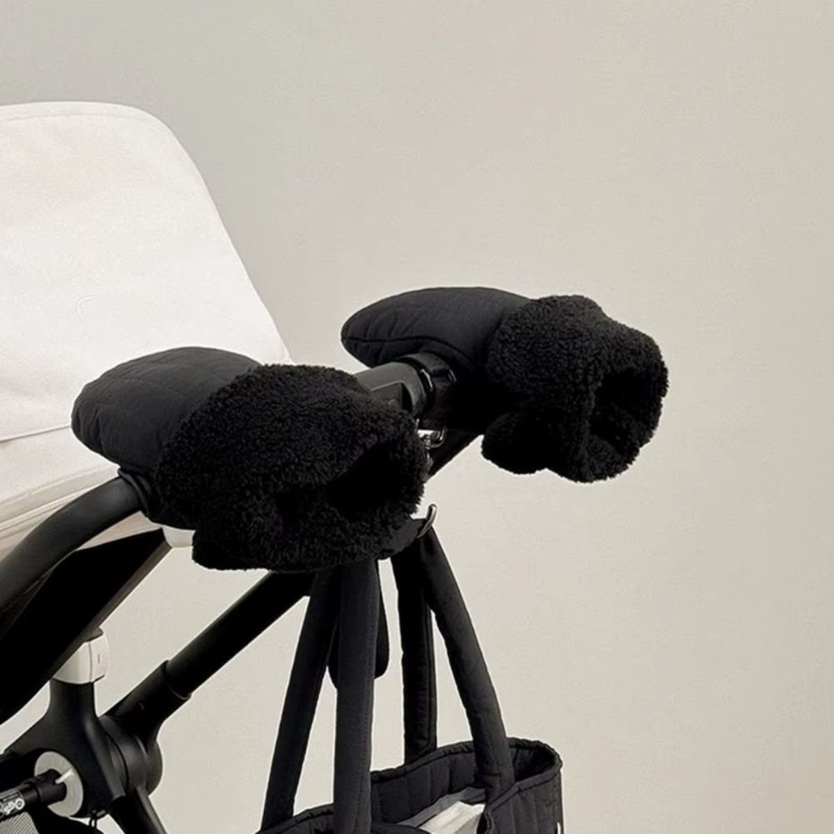Gros plan sur deux gants de poussette noirs avec larges ouvertures à revers effet bouclette