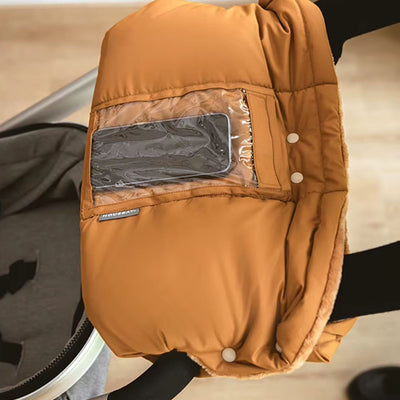Manchon poussette marron avec poche téléphone transparente et boutons-pression blancs, installé sur le guidon d'une poussette