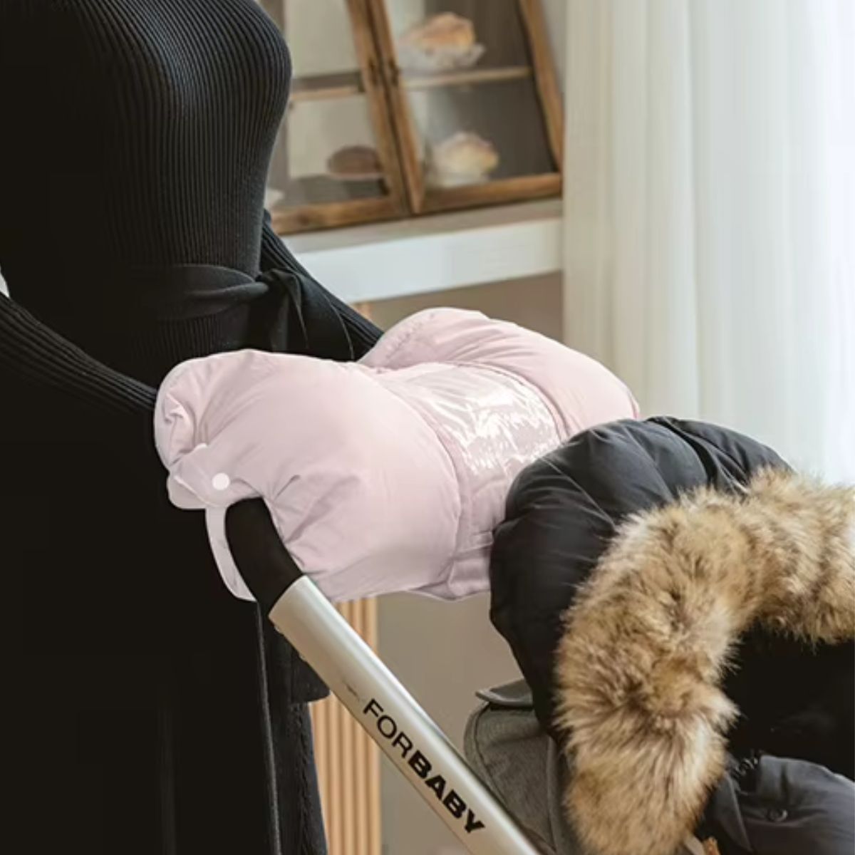 Manchon poussette rose avec deux ouvertures pour les mains, installé sur le guidon d'une poussette