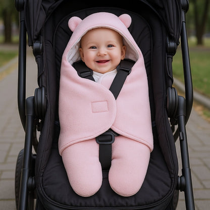 nid d’ange rose en coton hydrophile avec bébé souriant attaché dans une poussette noire, capuche douce et design épuré