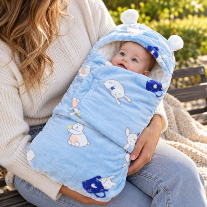 Nid d’ange bébé bleu clair à motifs lapins, avec capuche à petites oreilles et rabat frontal, sur les genoux d’une femme en pull crème
