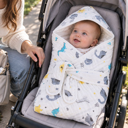 Bébé installé dans le nid d'ange gaze de coton à motifs dinosaures, avec pans croisés et deux bandes de maintien