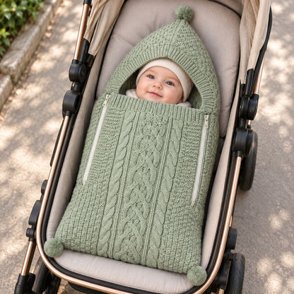 Nid d'ange tricot vert avec maille torsadée, capuche à pompon et deux zips latéraux