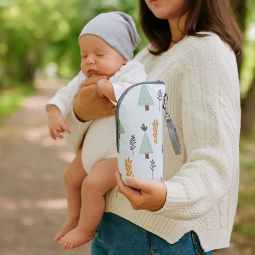Pochette imprimée pour biberon motif forêt tenue en main pendant une sortie avec bébé