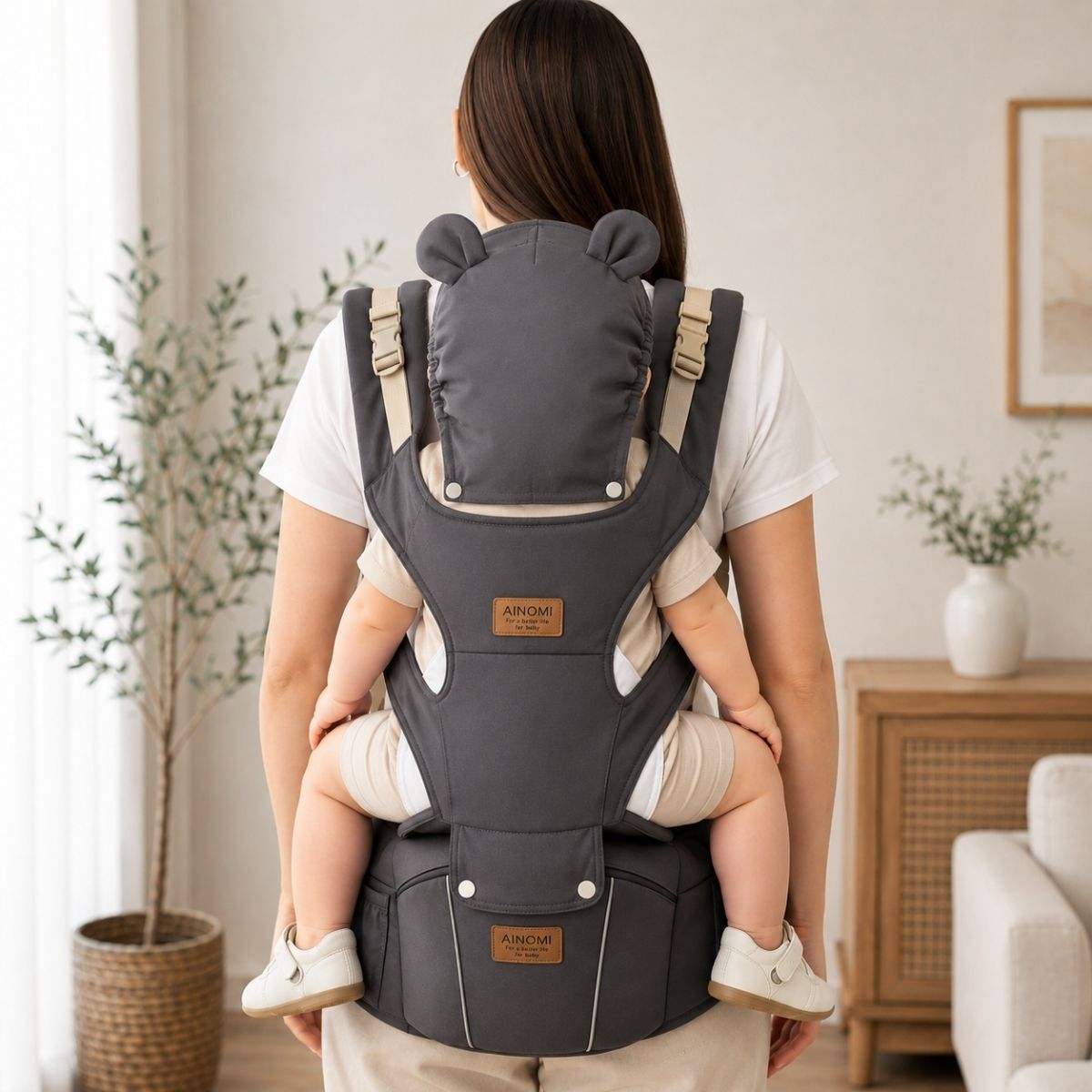 Porte-bébé 3 en 1 gris foncé avec siège de hanche et capuche amovible, utilisé en portage dorsal en intérieur