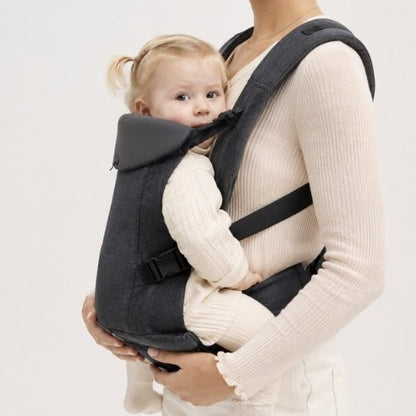 Porte-bébé à assise réglable gris clair avec bretelles rembourrées, enfant face au parent en intérieur