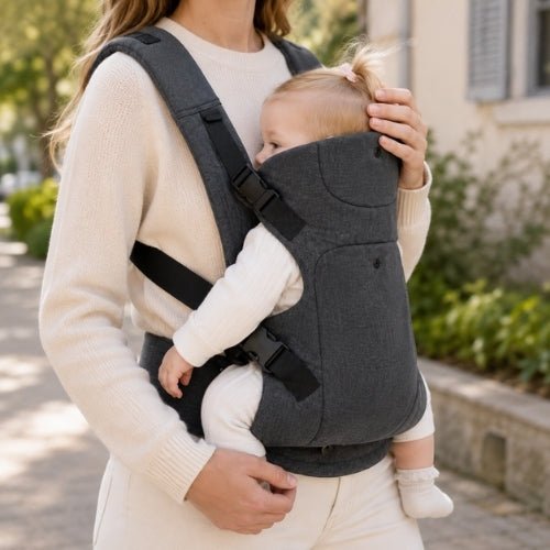 Porte-bébé à assise réglable gris foncé avec bretelles rembourrées, enfant face au parent en extérieur