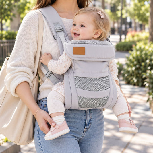Porte-bébé à boucle dorsale gris clair porté en extérieur, vue de face avec panneau inférieur en maille