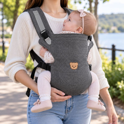 Porte-bébé à partie haute pliable gris foncé avec motif tête d’ourson, porté face au porteur près d’un lac