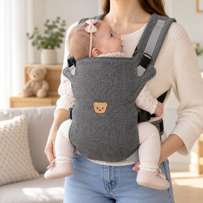 Porte-bébé à partie haute pliable gris foncé avec motif tête d’ourson, porté face au porteur en intérieur