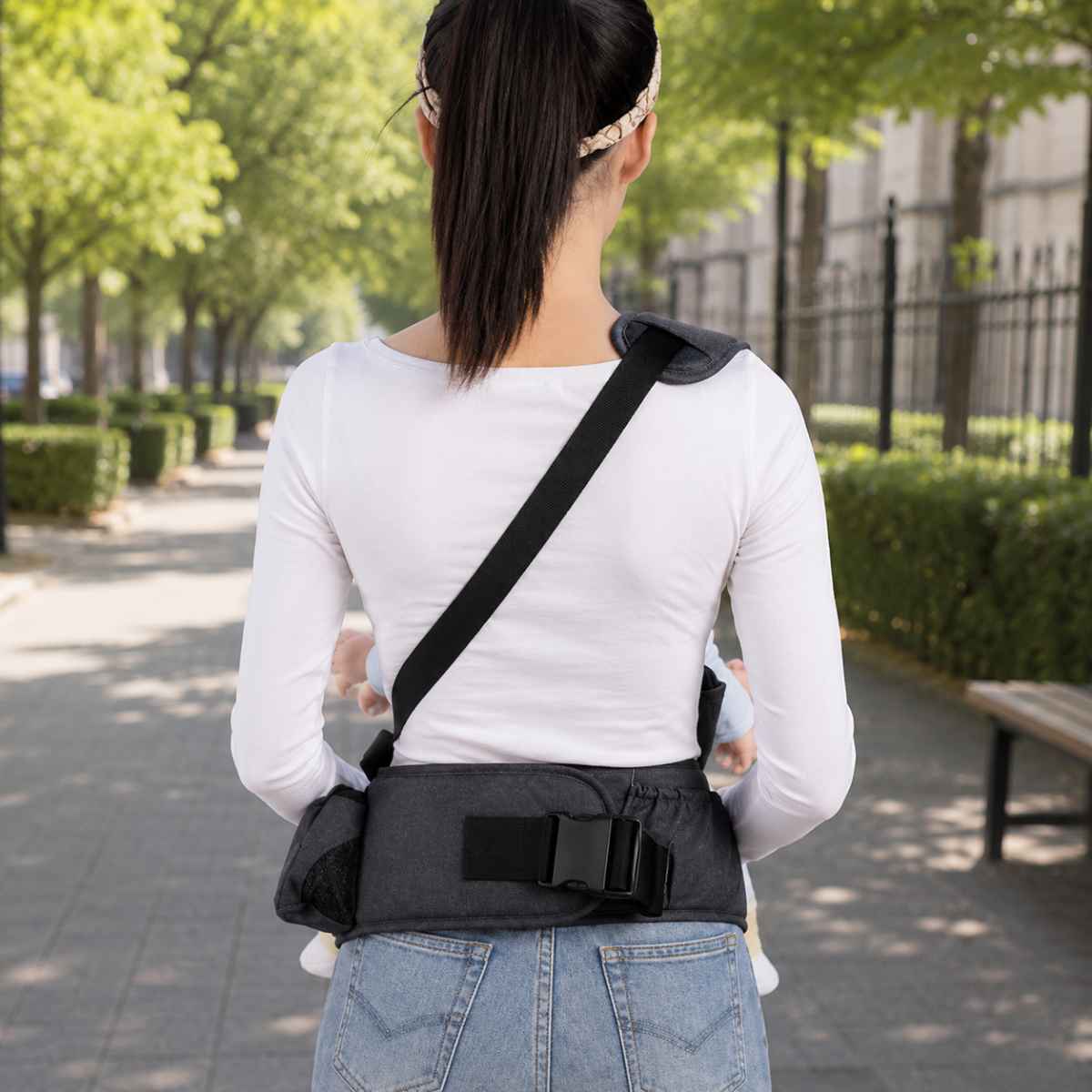 Porte-bébé à siège de hanche noir avec sangle d’épaule diagonale, vue arrière de la ceinture et de la boucle