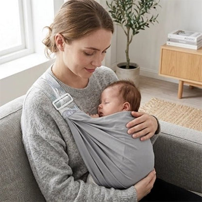 Porte-bébé à une épaule gris clair avec assise large et sangle réglable, utilisé en position horizontale en intérieur