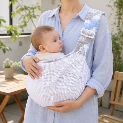 Porte-bébé à une épaule en maille blanche bleu gris avec assise large et sangle réglable, sur une terrasse
