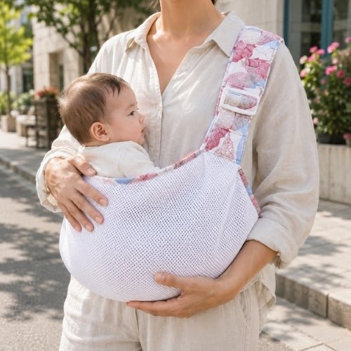 Porte-bébé à une épaule en maille blanche et rose avec assise large et sangle réglable, dans une rue