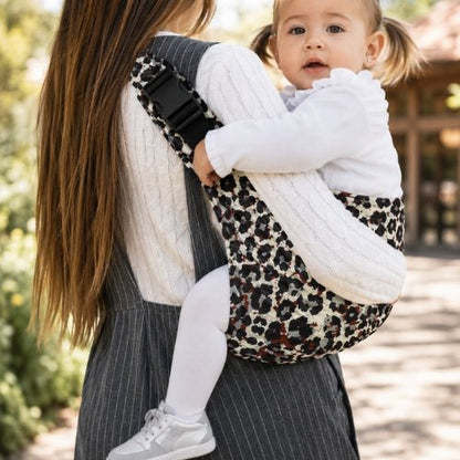 Porte-bébé à une épaule léopard clair avec épaulière large et boucle réglable, vue latérale en extérieur