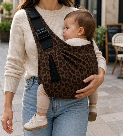 Porte-bébé à une épaule léopard avec épaulière large et boucle réglable, porté près d’une terrasse