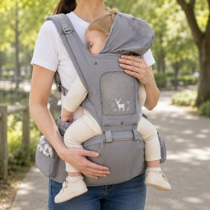 Porte-bébé avec capuche gris, protection textile supérieure déployée pendant le portage dans un parc