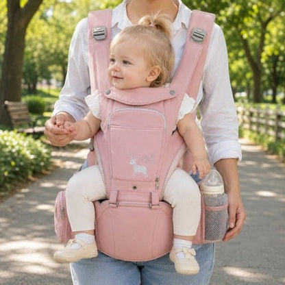 Porte-bébé avec capuche rose, panneau ouvrable et rangements, porté face vers l’avant dans un parc