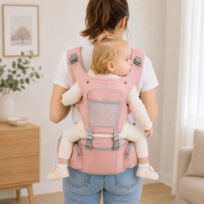 Porte-bébé avec capuche rose, panneau ouvrable et rangements, utilisé en portage dorsal en intérieur