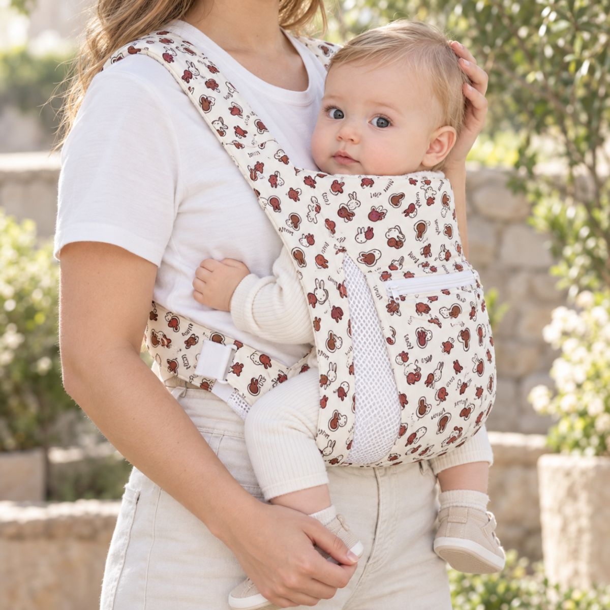 Porte-bébé avec capuche crème motif lapins, vue de face en extérieur avec bébé