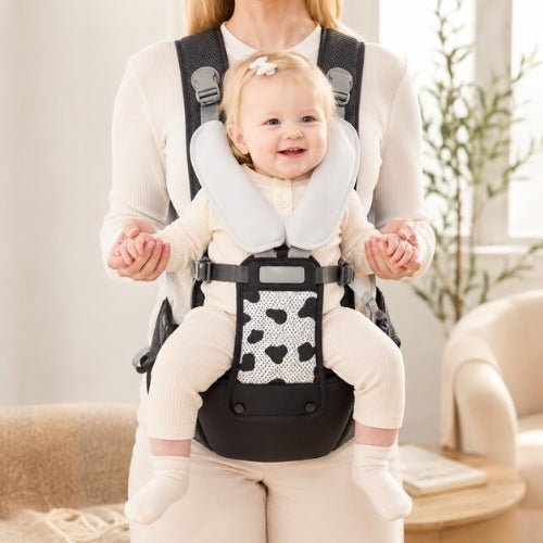 Porte-bébé avec siège détachable noir et gris, porté face vers l’avant dans un intérieur lumineux
