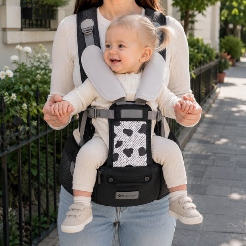 Porte-bébé avec siège détachable noir et gris, porté face vers l’avant dans une rue