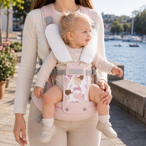 Porte-bébé avec siège détachable rose, porté face vers l’avant au bord de l’eau