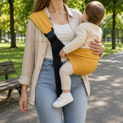Porte bebe bandouliere jaune moutarde avec boucle réglable, port latéral dans un parc