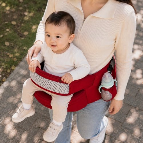Porte bebe cote hanche rouge porté sur le côté avec siège large, vue en hauteur