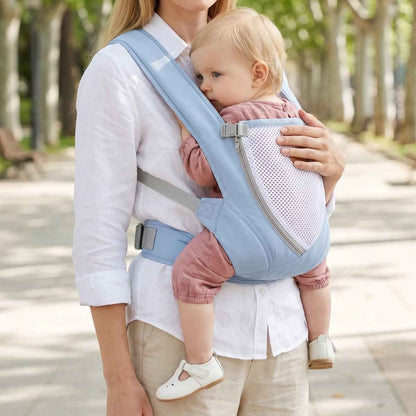 Porte-bébé croisé dans le dos bleu clair avec bretelles larges et panneau en maille, porté face au porteur dans un parc