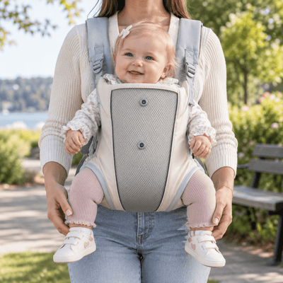 Porte-bébé facile à enfiler beige clair et gris, vue de face en extérieur avec bébé