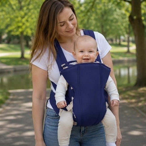 Porte bebe frontal bleu porté face vers l’avant dans un parc