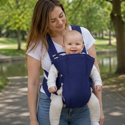 Porte bebe frontal bleu porté face vers l’avant dans un parc