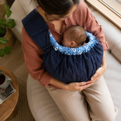 Porte bébé hamac bleu marine avec contour rembourré et sangle réglable, vue en plongée pendant le portage