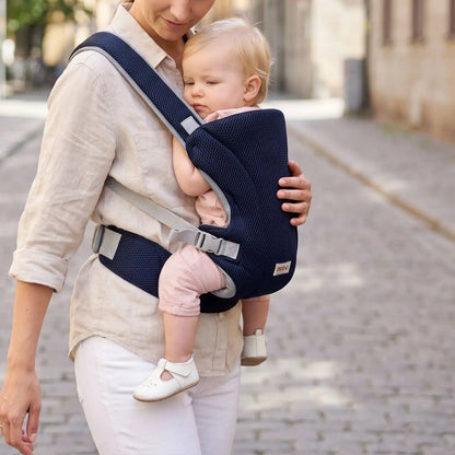 Porte-bébé mesh bleu marine avec bretelles croisées et format léger, porté face au porteur en ville