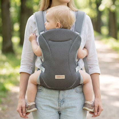 Porte-bébé mesh gris avec bretelles croisées et format léger, porté face vers l’avant dans un parc