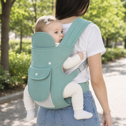Porte-bébé multiposition vert sauge avec panneau relevable et poche frontale, porté au dos en extérieur