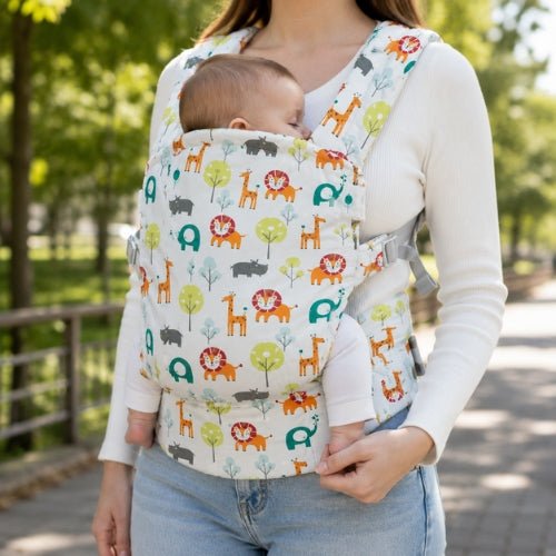 Porte bebe preforme à motifs animaux multicolores porté devant lors d’une promenade au parc