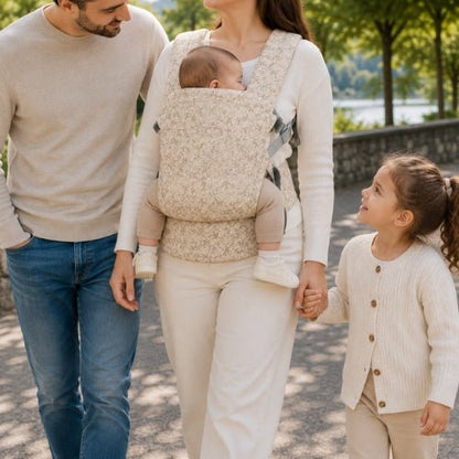 Porte bebe preforme beige fleuri porté devant lors d’une promenade en famille